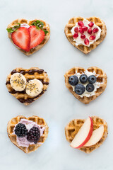 Mini heart shaped waffles topped with various spreads and fruit.