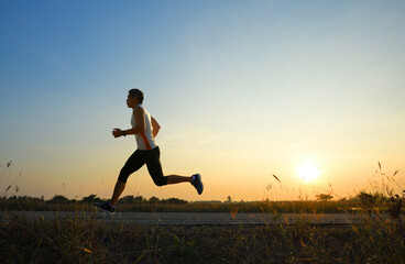 A man running and jogging on road with sunrise background.