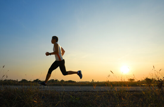 A man running and jogging on road with sunrise background.