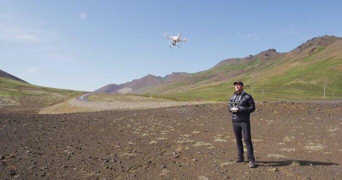 Drone pilot flying drone filming shooting video or taking photos on travel vacation in beautiful nature landscape on Iceland.
