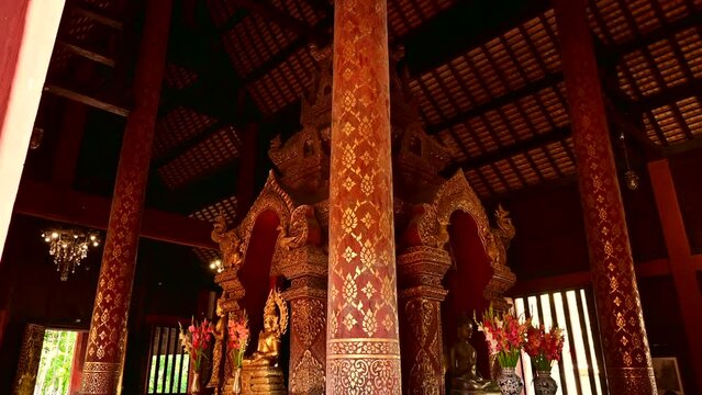 Old Buddha images in Lanna style wooden churches and ancient golden pagodas in Wat Phra Singh, Chiang Mai province.