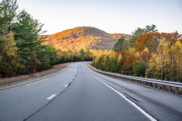 Autumn landscape with a winding road framed by yellow and red maples in the rolling hills of New Hampshire in New England