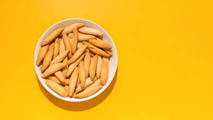 Top view of picos - bread sticks in the bowl on the yellow background with hard shadow and copy...