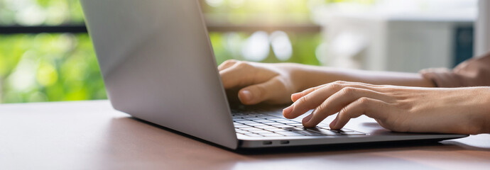 Hand using computer laptop and touching mouse on the table.