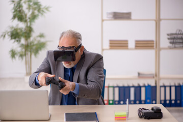 Old male employee enjoying virtual glasses at workplace