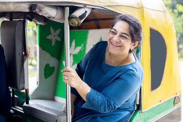 Happy mature indian woman enjoying rickshaw ride.