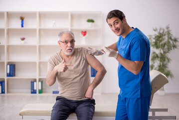 Obraz premium Old male patient visiting young male doctor in vaccination conce