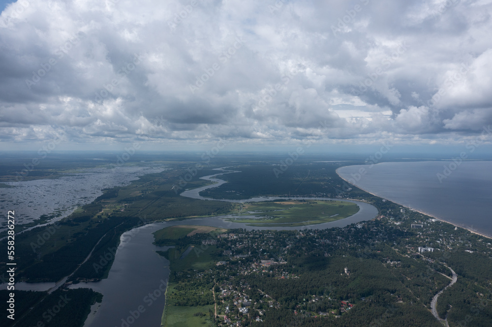 Poster an aerial view of a river and a city under a cloudy sky with a river running through the center of t