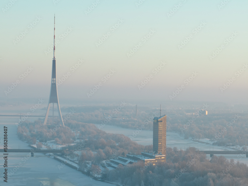 Poster a view of a river and a tall tower in the distance with trees in the foreground and a bridge in the 