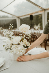 Florist arranging white peony flower on a wedding reception table