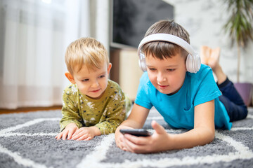 Two children watching smart phone, happy kids using smartphones together