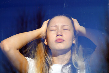 A teenage girl is reflected in the window in sunny weather. Psychology
