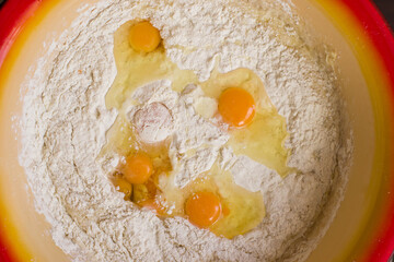 A close-up shot of a bowl of flour and an egg from above