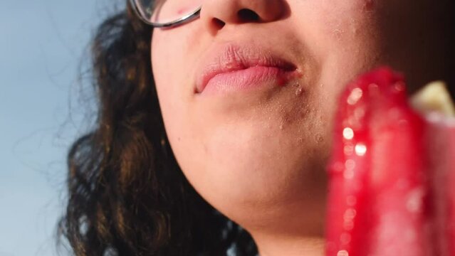Girl with braces biting a red ice cream in summer