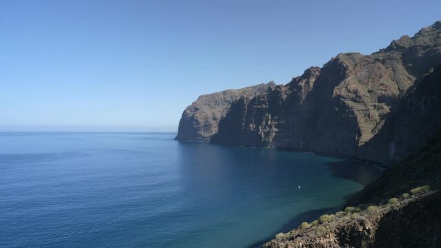 Los Gigantes Cliffs, Tenerife. Locked of tripod shot with calm waves and a solitary boat.