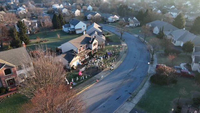 Christmas decorations on homeowner lawn during day. Festive holiday inflatables and light displays in community neighborhood. Aerial view.
