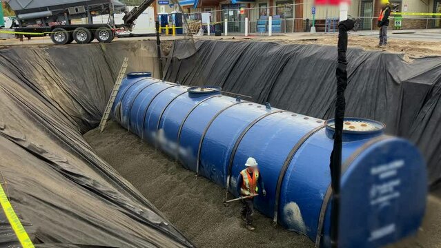 Rock Slinger Truck Fills large Diesel Underground Fuel Tank with Pea Gravel During Construction