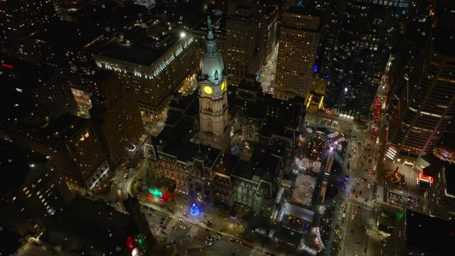 Philadelphia City Hall at night. Christmas tree is decorated and lit during winter snow storm. Snowflakes in aerial shot.