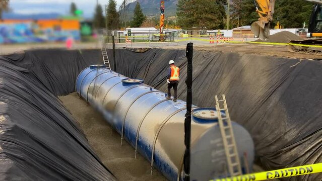 Construction Crew Using Rock Slinger Truck to Fill In Underground Fuel Tank with Pea Gravel