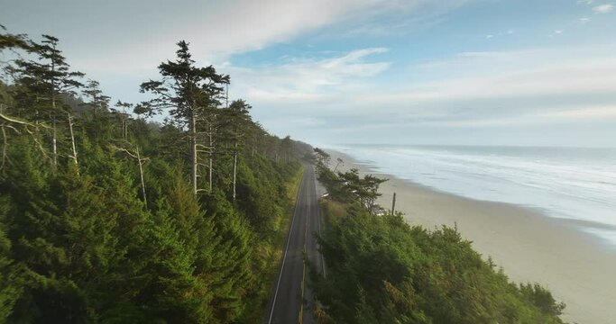 Long drone flight over the pacific ocian road in Washington state USA. Coast line, trees, road anc ocean are visible. High quality 50fps footage.