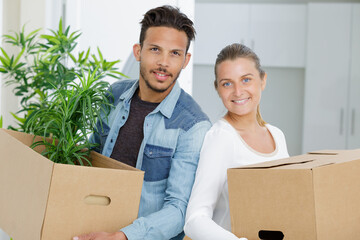 young couple unpacking cardboard boxes at new home