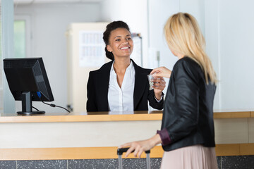 hotel receptionist giving key to female visitor