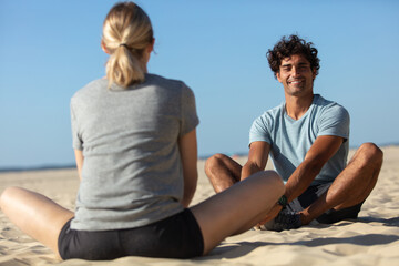 couple making yoga exercises sitting on beach outdoors