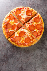 Hot homemade Pepperoni pizza ready to eat close-up on a wooden board on the table. Vertical top view from above