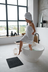 Young woman wearing white towel on head and body coming out of bath