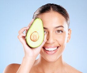 Woman, studio portrait and avocado skincare with smile, health or wellness by blue background....