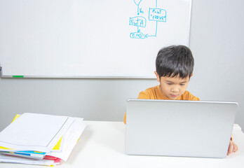 Asian school boy using laptop computer on desk at home for Online education concept.