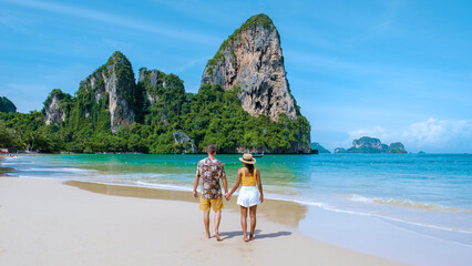 Railay Beach Krabi Thailand, the tropical beach of Railay Krabi, a couple of men and women on the beach, Panoramic view of idyllic Railay Beach in Thailand with a traditional long boat. © Fokke Baarssen