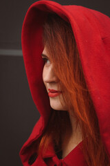 Close up positive young woman wearing coat with red hood portrait picture. Closeup side view...