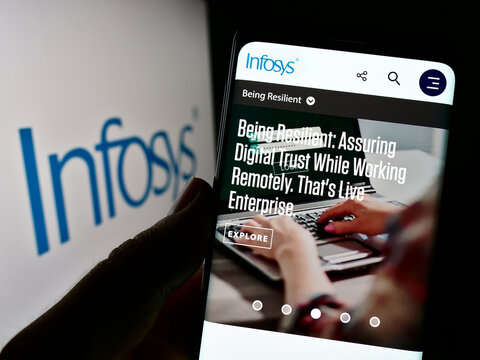 Stuttgart, Germany - 12-23-2022: Person holding cellphone with webpage of Indian IT company Infosys Limited on screen in front of logo. Focus on center of phone display.