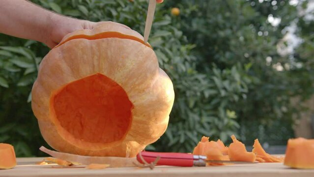 Preparation for carving pumpkins. Man puts a pumpkin on the board