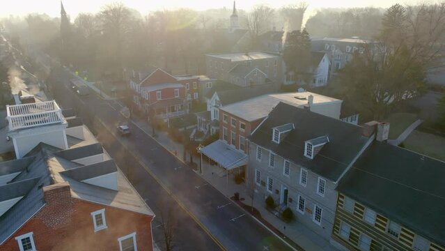 Main Street in historic small town. Church and old houses and homes. Aerial on foggy morning with sunlight.