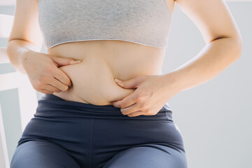 Beautiful fat woman with tape measure She uses her hand to squeeze the excess fat that is isolated on a white background. She wants to lose weight, the concept of surgery and break down fat under the