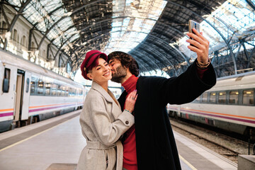 Couple kissing while taking a selfie in a train station