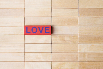 Red wooden block with the caption Love over wooden blocks. Valentine's day greeting concept