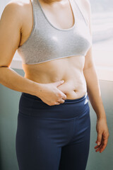 Beautiful fat woman with tape measure She uses her hand to squeeze the excess fat that is isolated on a white background. She wants to lose weight, the concept of surgery and break down fat under the