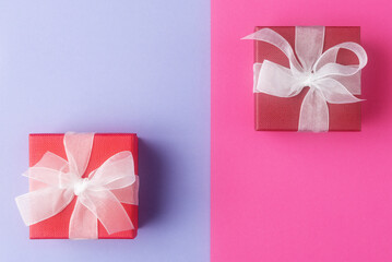 Red gift boxes with white bows on blue pink background
