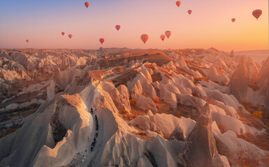 Horse tourist tour on rose valley of Cappadocia Turkey, national park Goreme with hot air balloons. Aerial top view landscape sunset © Parilov