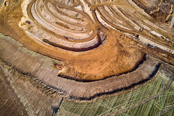 Aerial view of a growing sand pit at the expense of fields, overburden removal by excavators before...