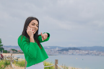 woman with mobile phone pointing a direction on the beach promenade