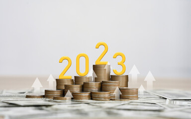 Gold wooden number year 2023 on top stack of coins for saving money and financial plan concept for...