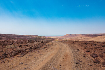 Fototapeta na wymiar A dirt road in the panoramic desert landscapes of Loiyangalani District in Turkana, Kenya