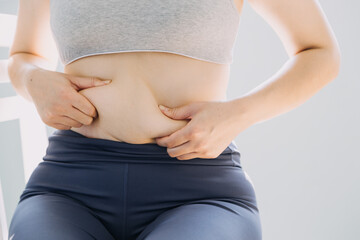 Beautiful fat woman with tape measure She uses her hand to squeeze the excess fat that is isolated on a white background. She wants to lose weight, the concept of surgery and break down fat under the