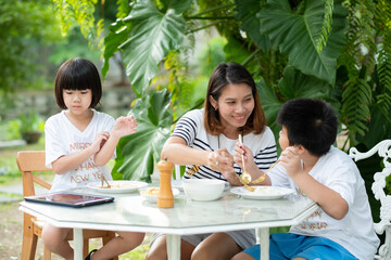 Asian children enjoy eating food with their mother