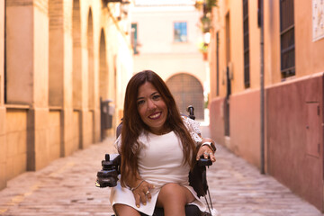 Woman with disability, reduced mobility and small stature in an electric wheelchair posing happily...
