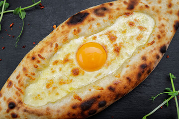 Adjarian khachapuri with egg and cheese on a black